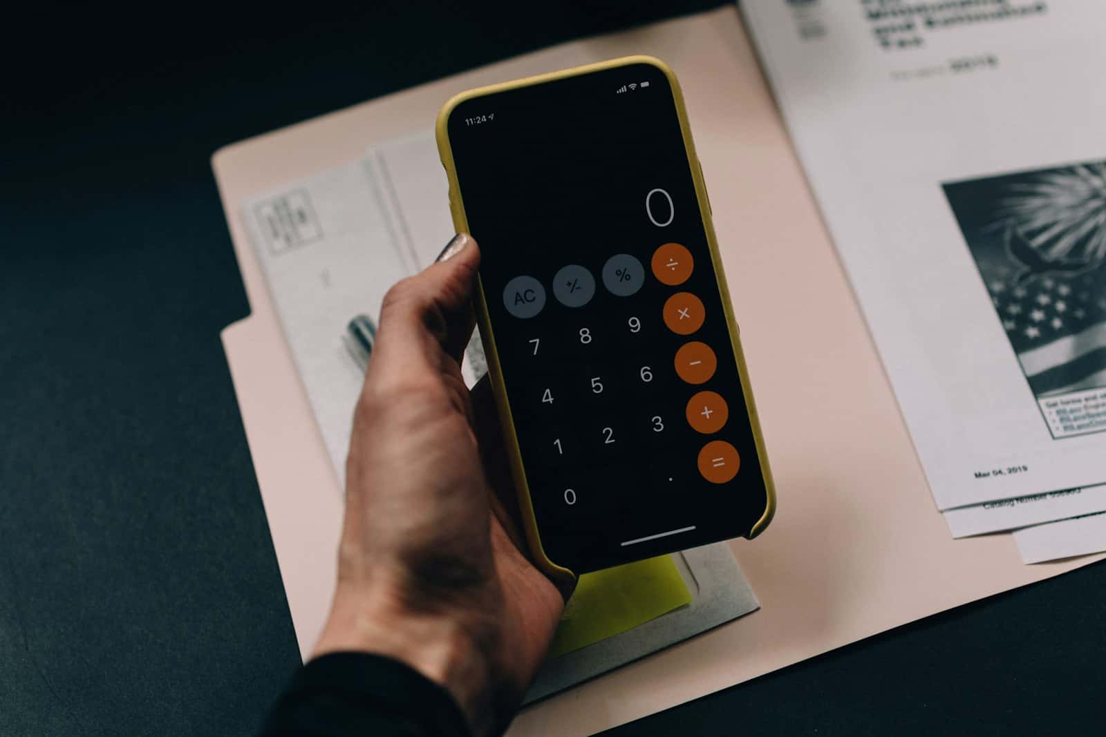 Belgeler üzerinde telefonla hesap makinesi kullanan el