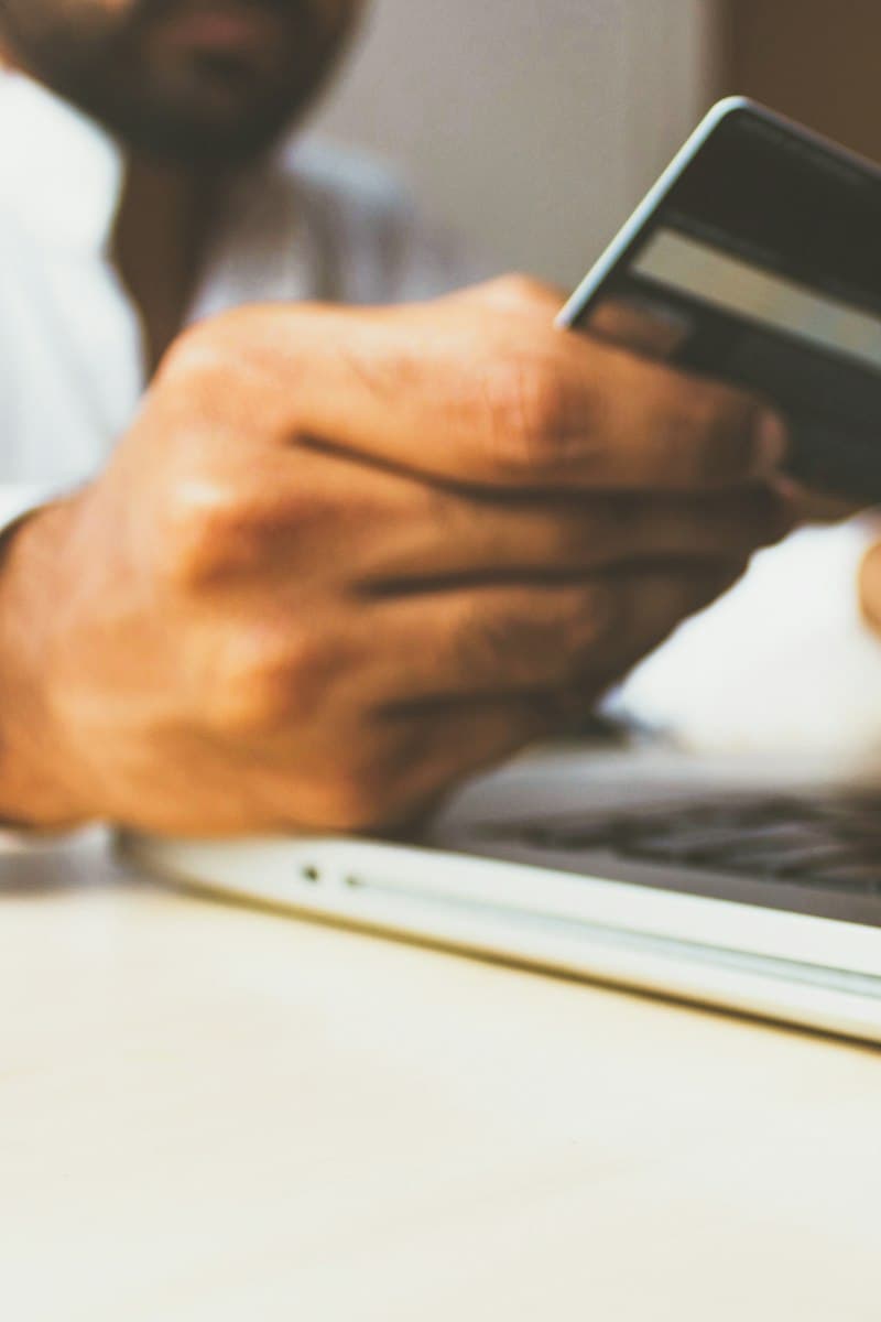 Dizüstü bilgisayar önünde kredi kartıyla internetten alışveriş yapan el